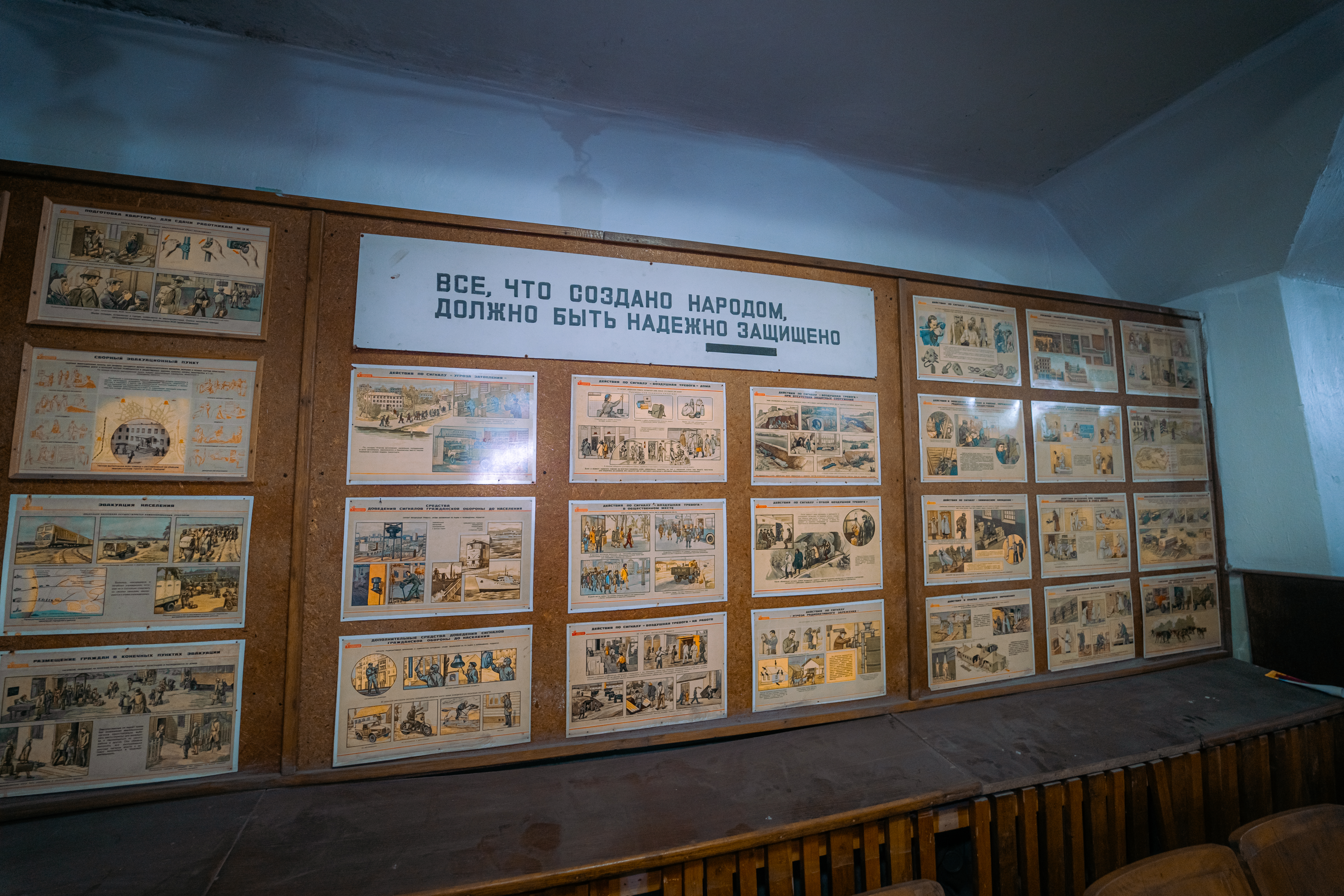 A cork board filled with illustrated panels depicting historical events, with a prominent sign stating 'Everything created by the people must be reliably protected' above it.