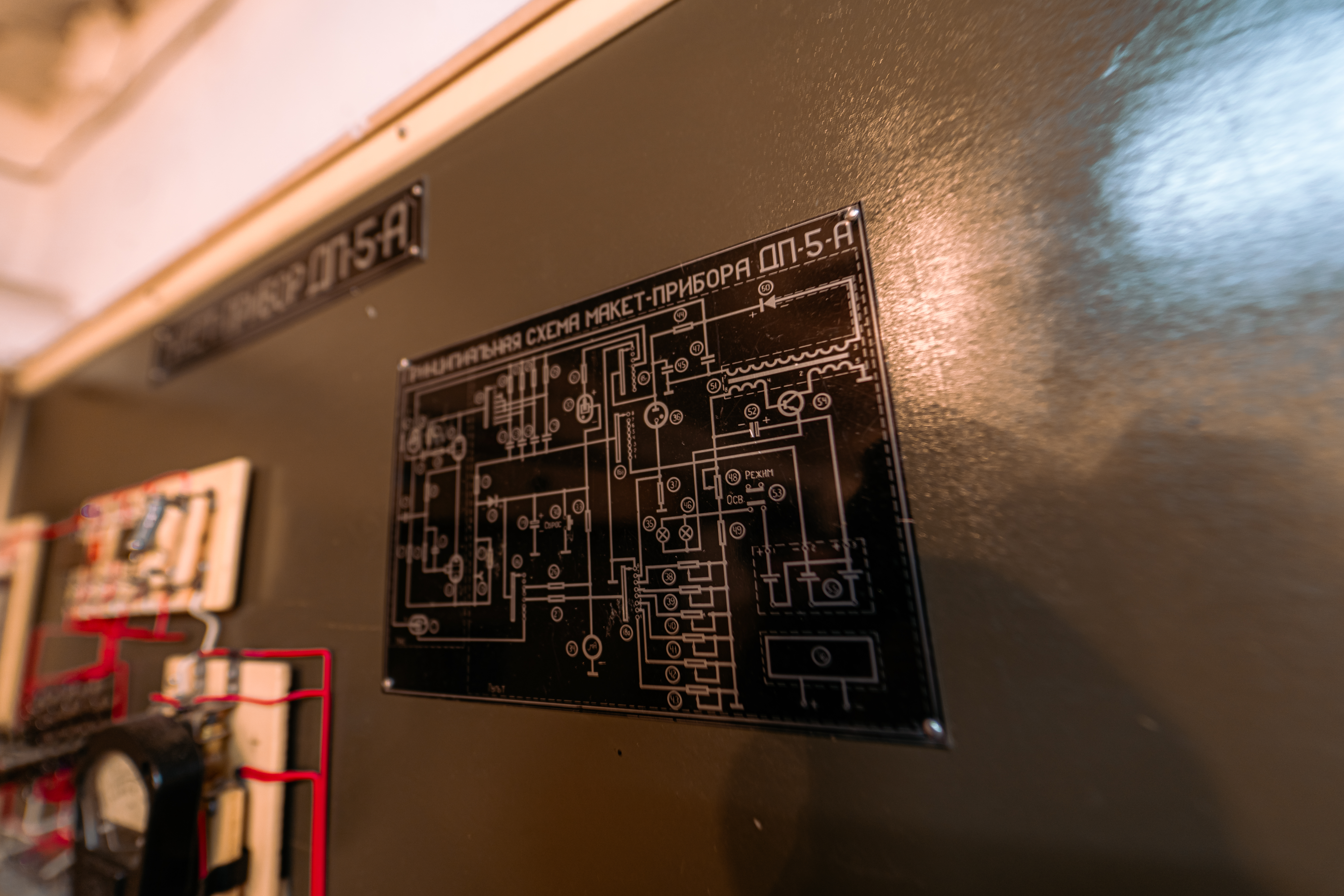 Close-up of a circuit schematic on a metallic panel with intricate designs and connections, illuminated by warm lighting.
