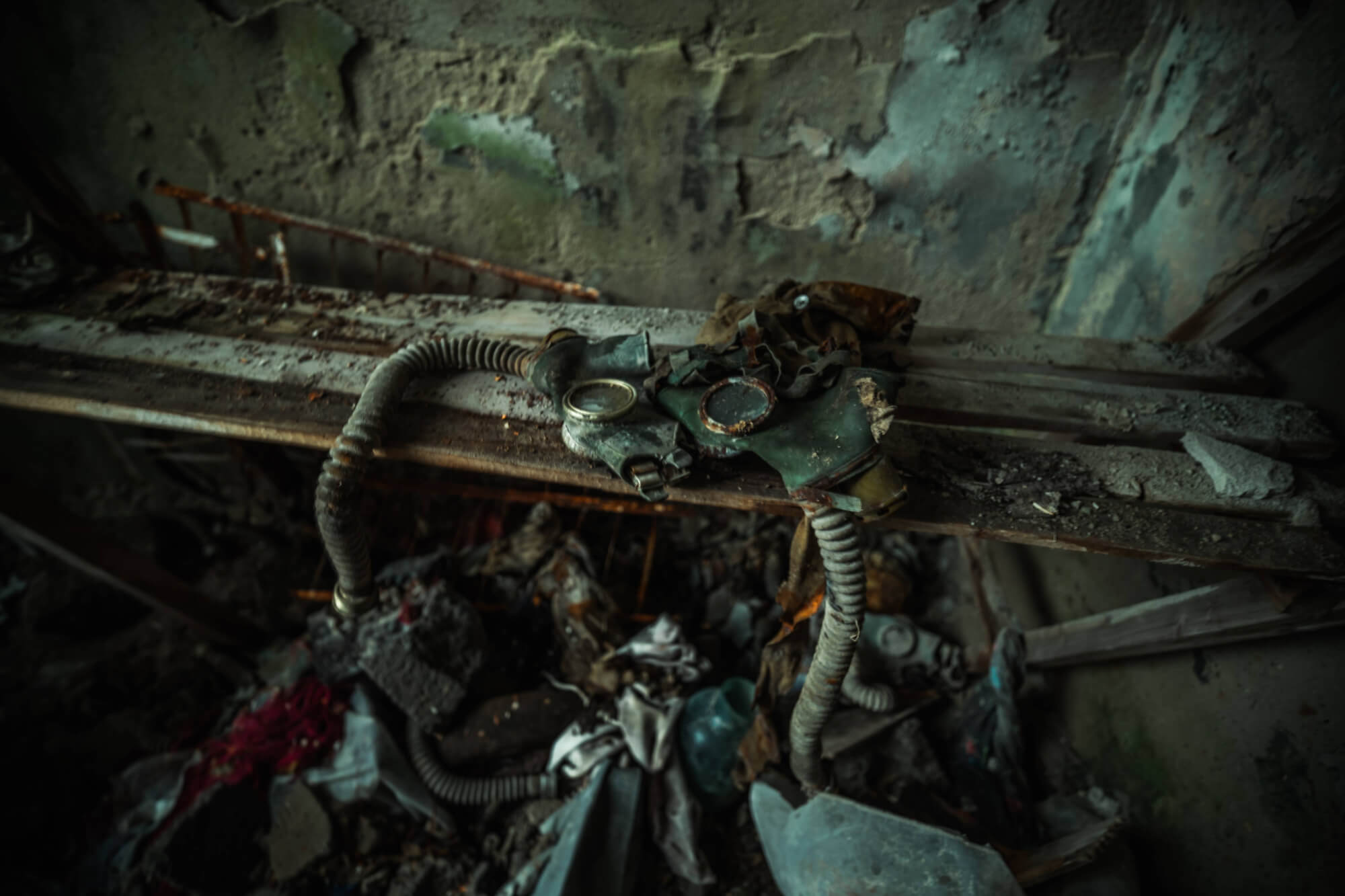 A worn gas mask lying on a dusty wooden surface, surrounded by debris and remnants of decay.