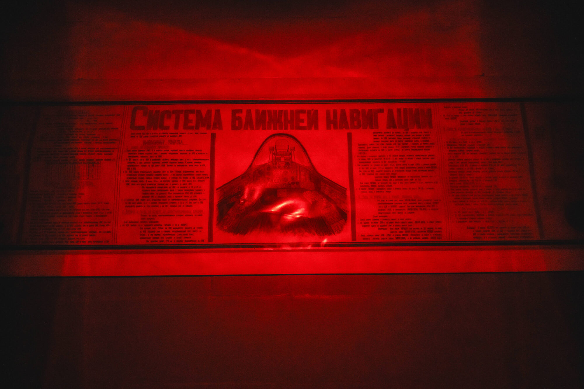 A newspaper clipping illuminated in red, showing a navigational system design and surrounding text in a dark setting.
